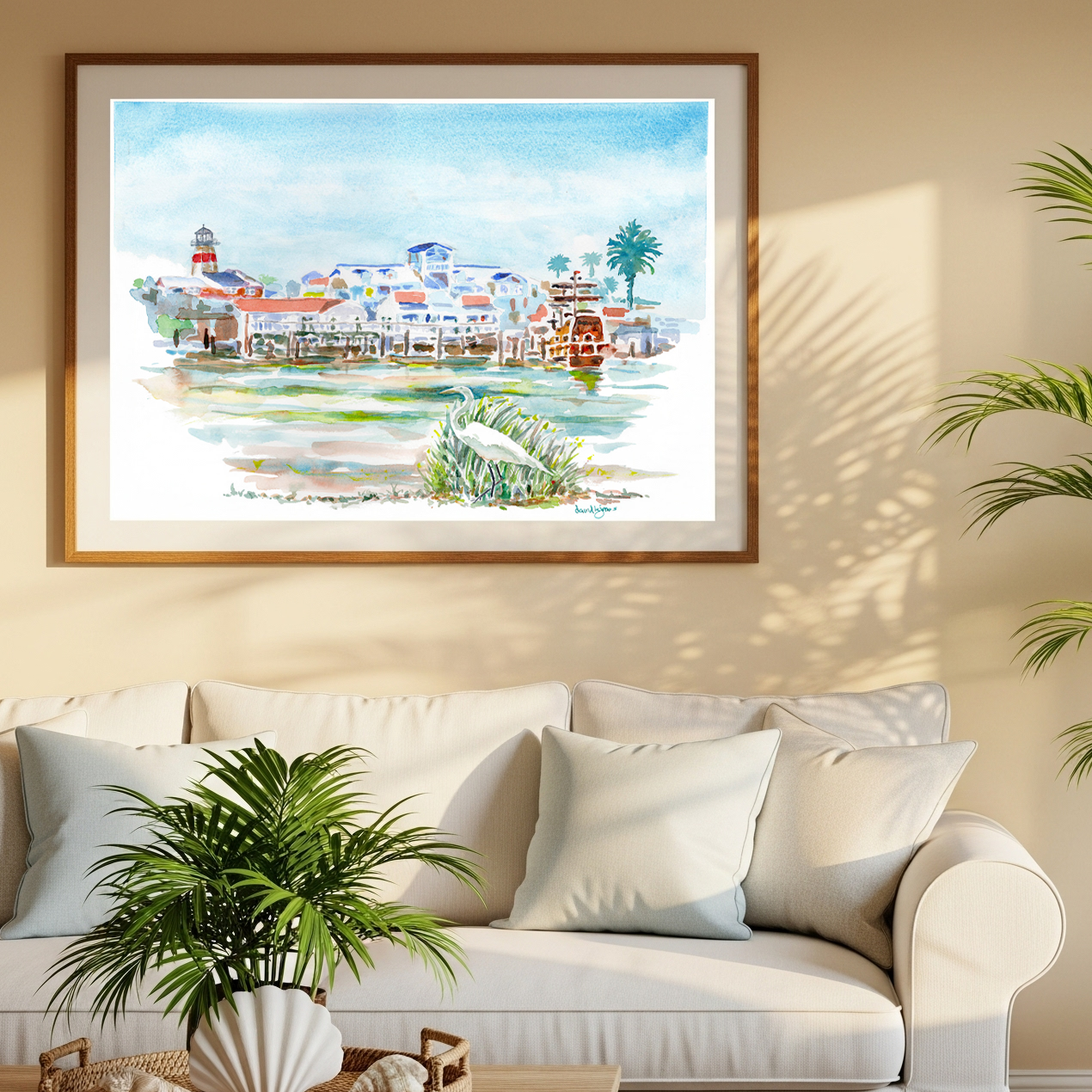 "Paradise at the Pass" watercolor print of Johns Pass Village, Madeira Beach, Florida, by artist David K. Jones.displayed on a beige wall above a white sofa in a styled living room setting.