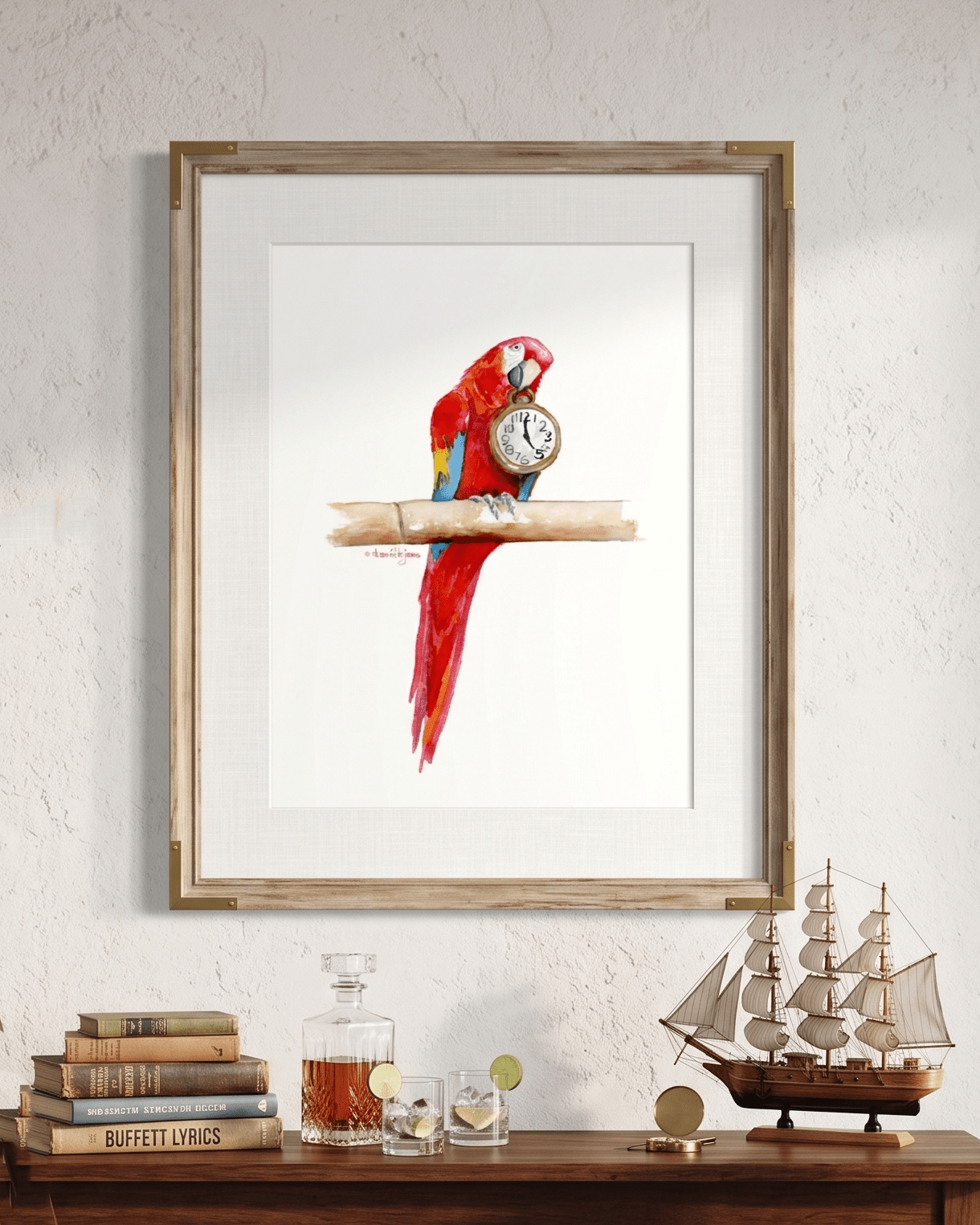 Framed watercolor painting by artist David K. Jones titled "It's Five O'clock HERE," featuring a vibrant scarlet macaw parrot perched on a bamboo branch against a clean white background. The red, blue, and yellow parrot holds a vintage pocket watch in its beak, with the hands explicitly pointing exactly to 5:00. Hung over a desk with a Jimmy Buffett lyric book and two poured drinks.